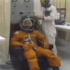 Crewmembers don their orange spacesuits